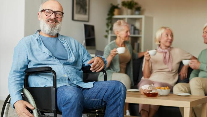 Senior Man Sitting in Wheelchair with Family Behind him