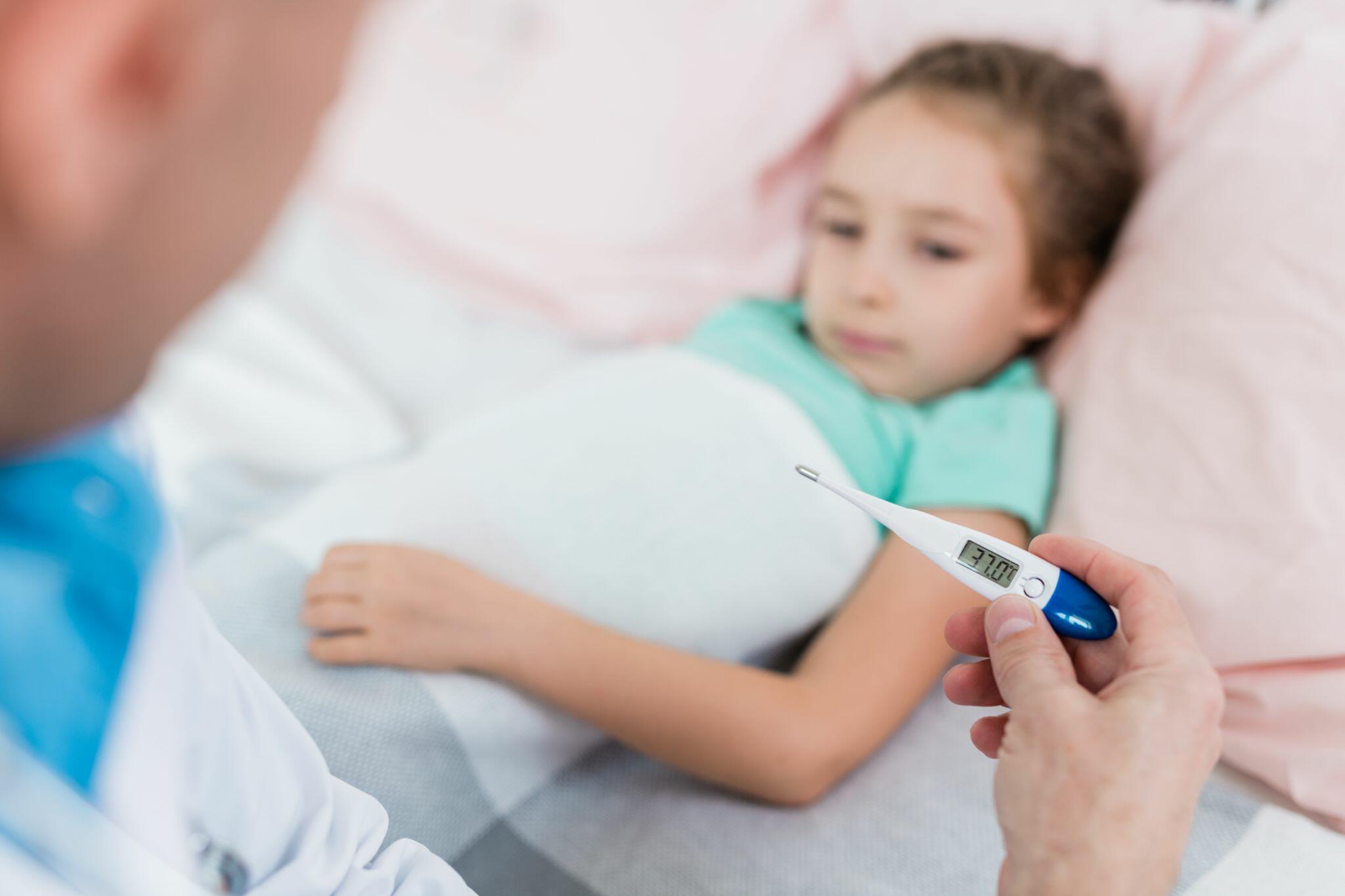 Doctor Taking Young Patient's Temperature with Medical Thermometer