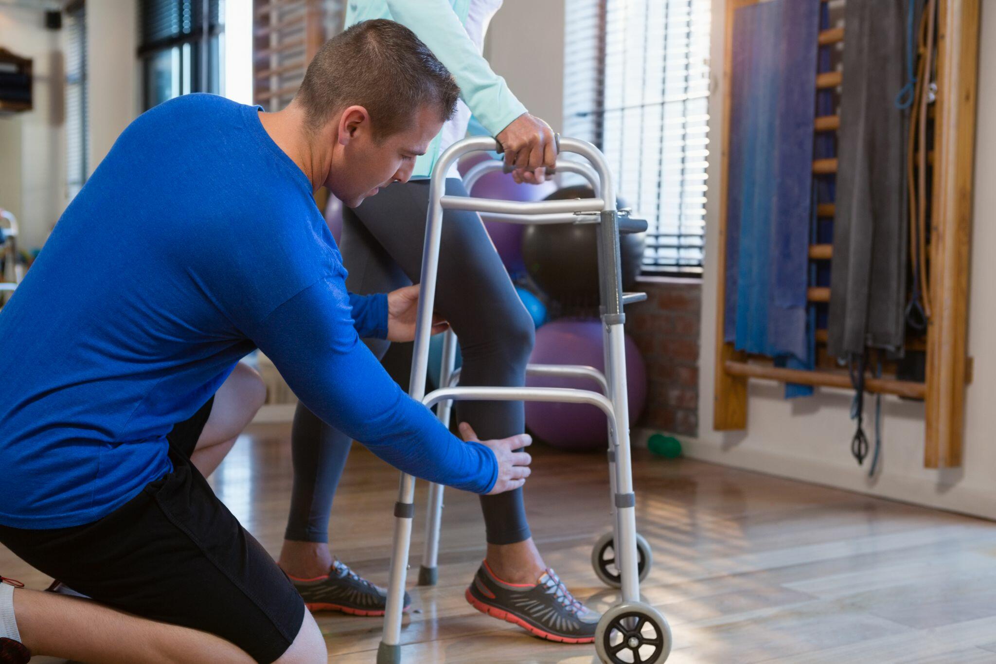 Physiotherapist Helping Patient to Walk With Walker